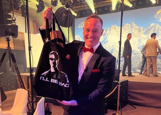 Matt Iseman präsentiert ein dunkles goodbag mit Arnold Schwarzenegger Design.