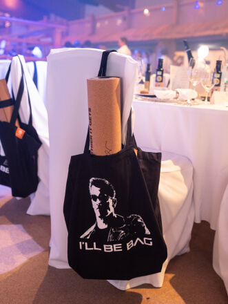 Eine Arnold Schwarzenegger goodbag hängt an einem Stuhl.