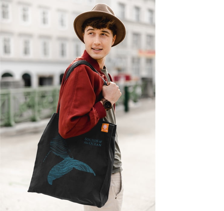 A guy with a black tote bag with a whale design 