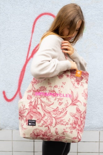 A woman with an upcycled white goodbag with a pink flower print