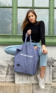 A woman holding an upcycled gray goodbag tote bag produced with TwoLives