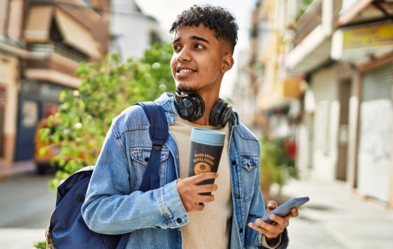Um jovem segurando um goodcup e um celular com o aplicativo goodbag.